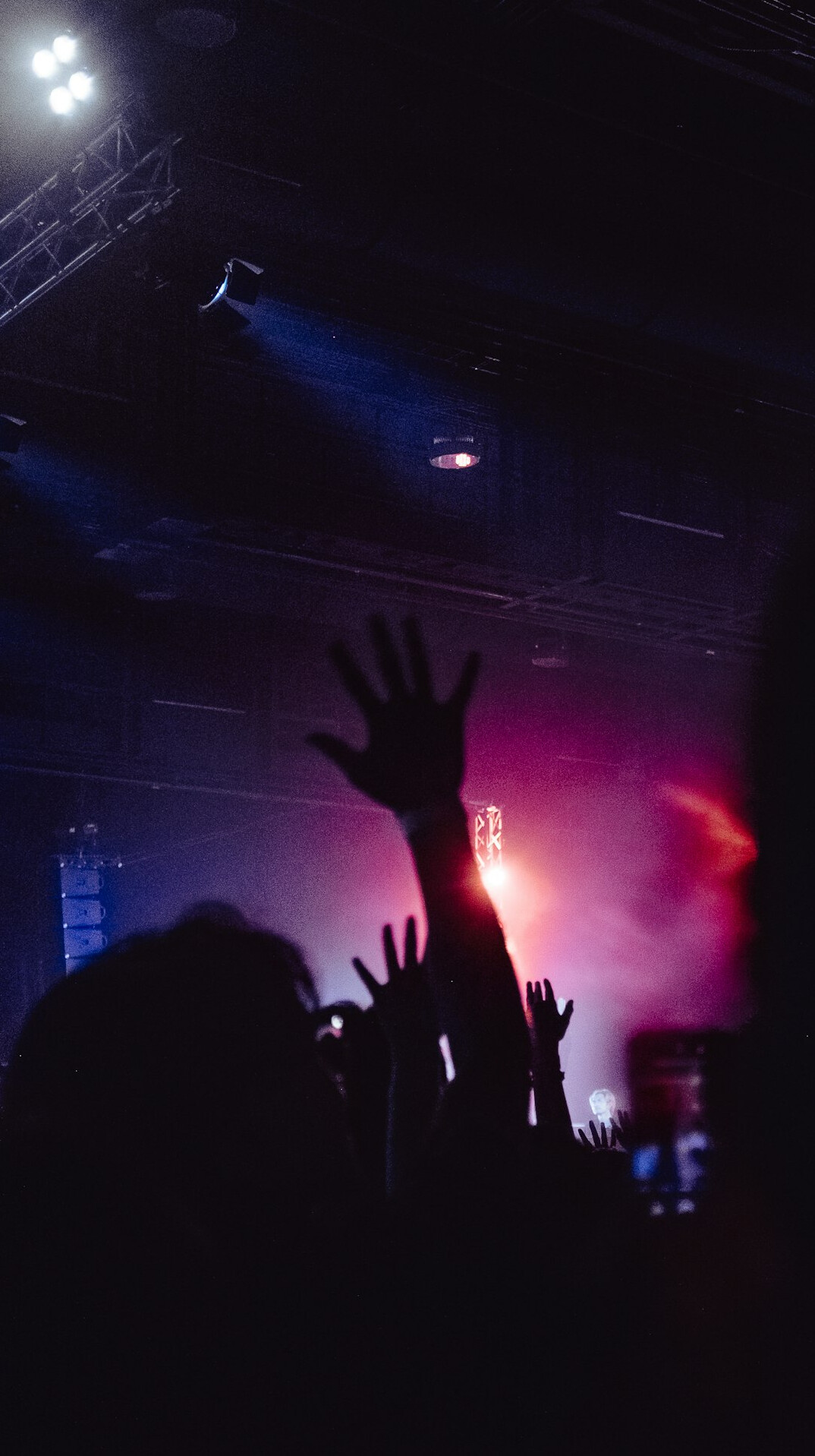 Concert crowd with hands in the air under stage lights